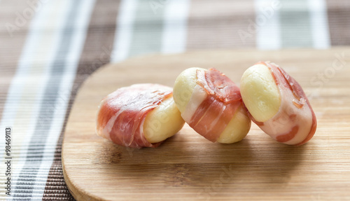 Mini cheese and prosciutto wraps on the wooden board photo