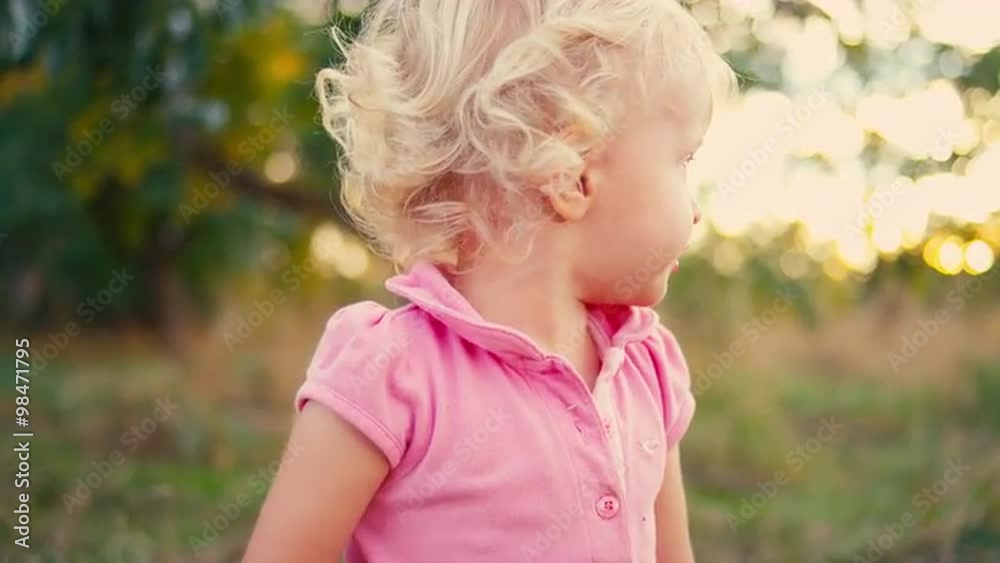 A cute little girl playing with a feather in a field A cute little girl playing with a feather in a field
