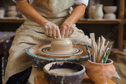 Fotografija hands of a potter, creating an earthen jar on the circle