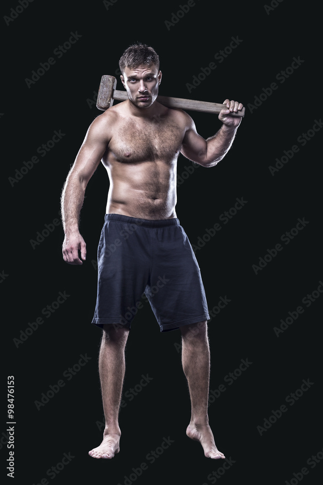 Sportsman with a sledgehammer next to tire isolated on black