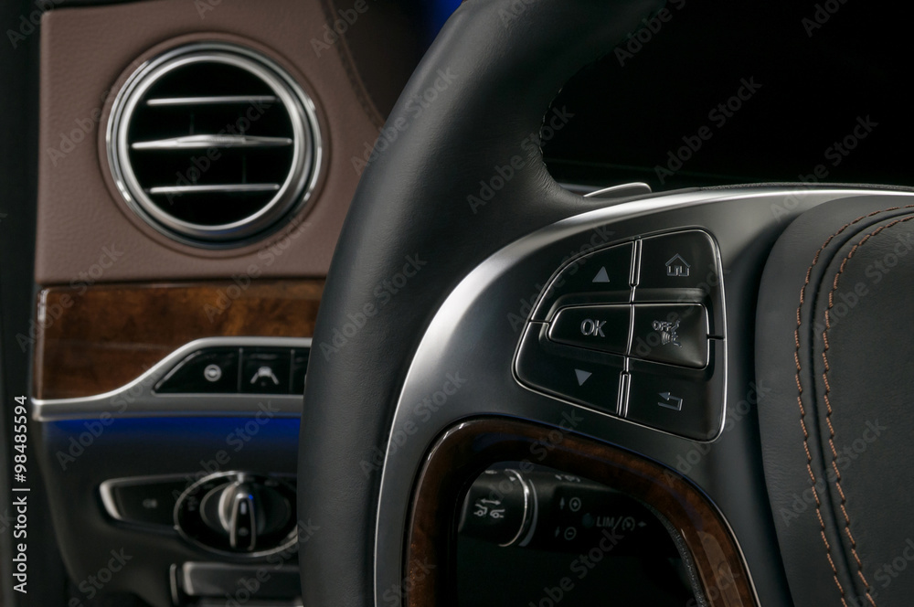 Control buttons on steering wheel. Modern car interior background.