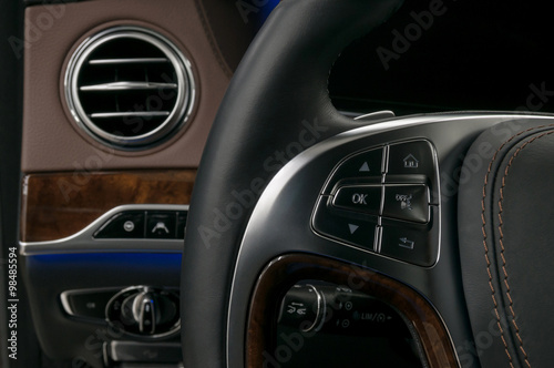 Control buttons on steering wheel. Modern car interior background. © alexdemeshko