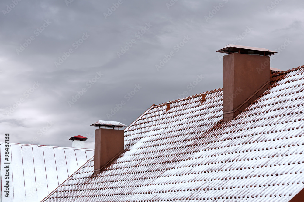 two red chimneys on roof covered with snow