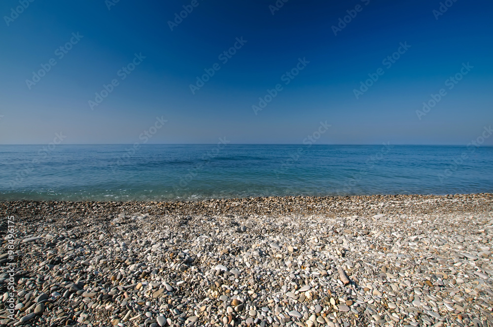 Sea gravel shore or beach and deep blue sky