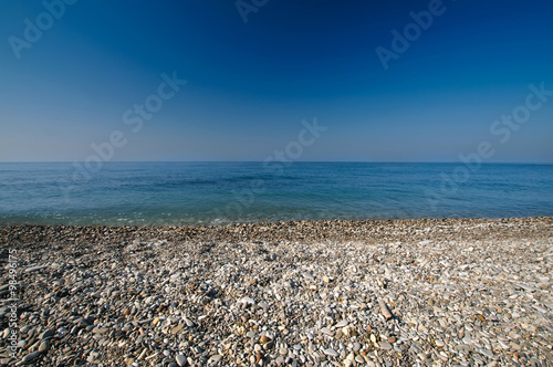 Sea gravel shore or beach and deep blue sky
