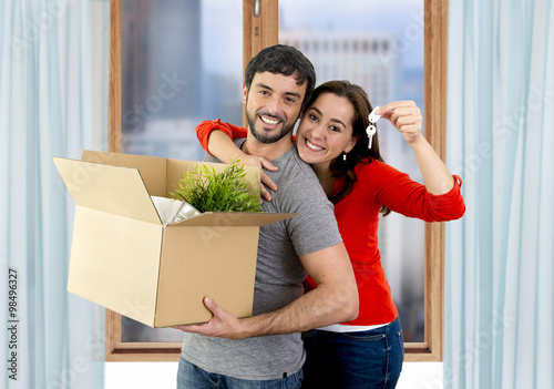 happy couple moving together in a new house unpacking cardboard boxes
