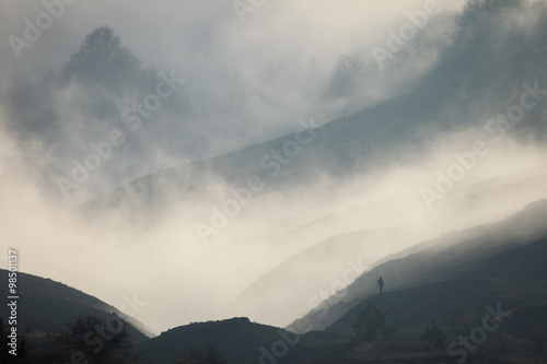 Silhouette of a man in a fog against the backdrop of mountain sl