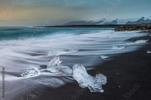 Ice cube with smooth wave at black sand beach Iceland during sunrise