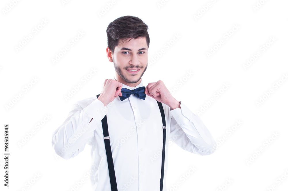 Young man correcting his bow tie, smiling. Isolated on white bac Young man correcting his bow tie, smiling. Isolated on white bac