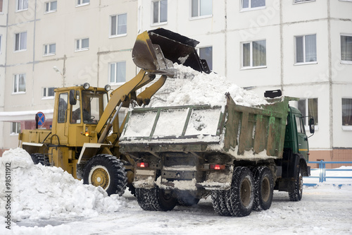 Tractor loads into the car body snow gathered in  yard