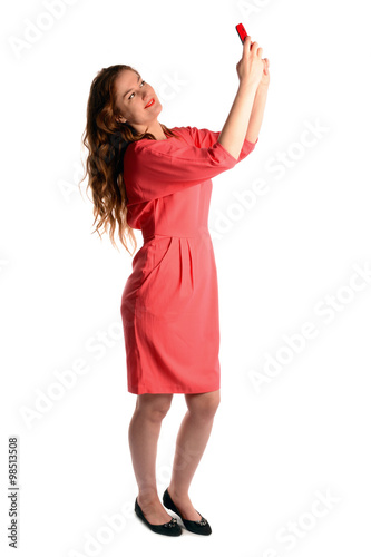 Smiling happy relaxed beauty taking self portrait with cellphone. Full body length portrait isolated over white studio background