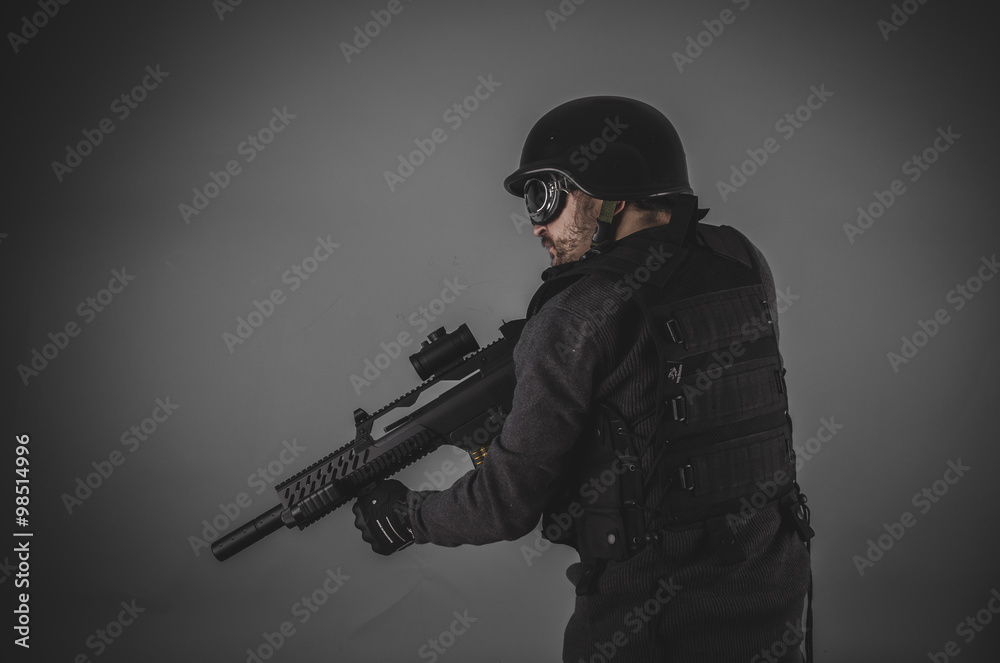 airsoft player with gun, helmet and bulletproof vest on gray bac airsoft player with gun, helmet and bulletproof vest on gray bac