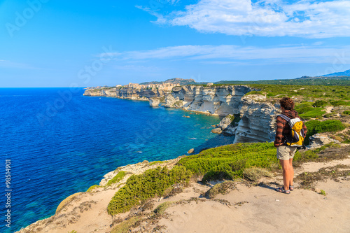 Young woman tourist on coastal path to Bonifacio old town built on high cliff above the sea, Corsica island, France