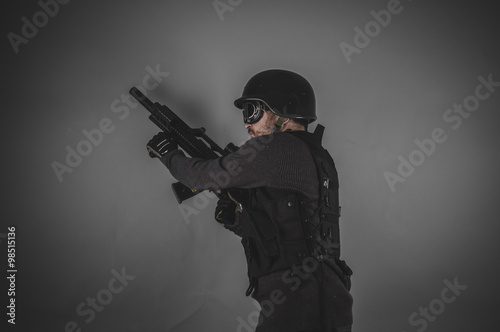 airsoft player with gun, helmet and bulletproof vest on gray bac © Fernando Cortés