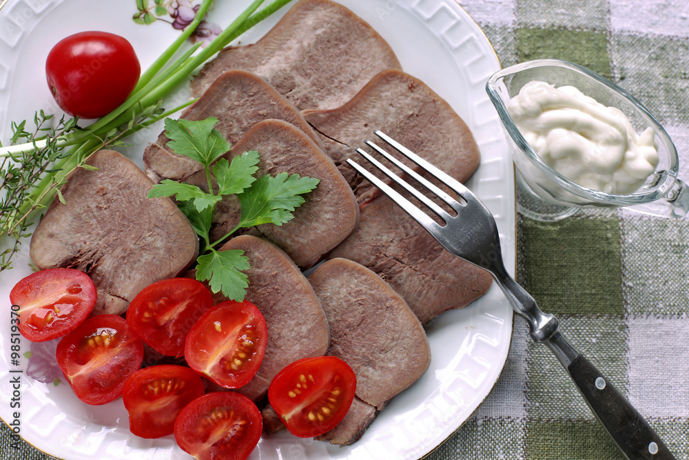 Sliced tongue on plate with parsley, tomato