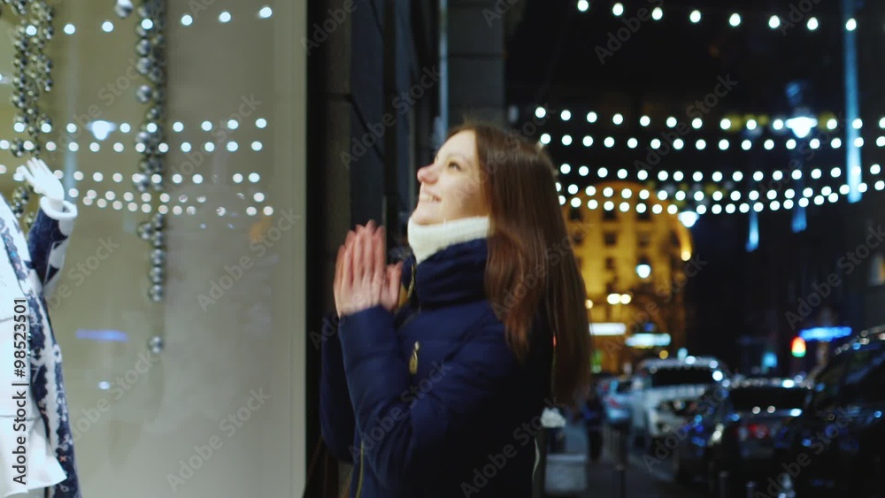 Beautiful young woman looking at a big shop window Beautiful young woman looking at a big shop window