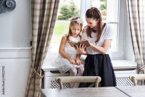 Caring mother teaching daughter how to read