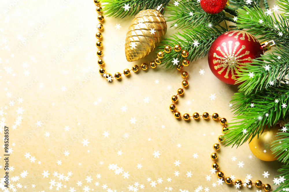 Christmas fir tree branches with toys and beads on paper background Christmas fir tree branches with toys and beads on paper background