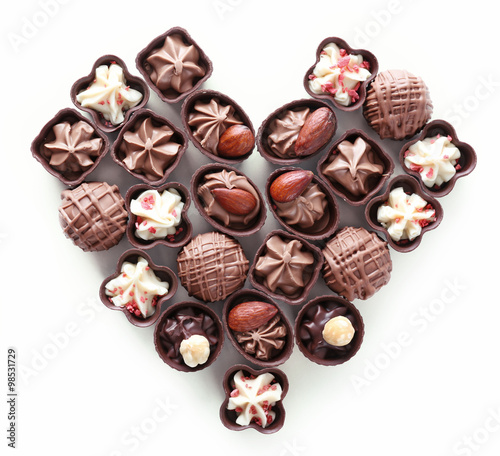 Heart shape composition of chocolate candies on white background