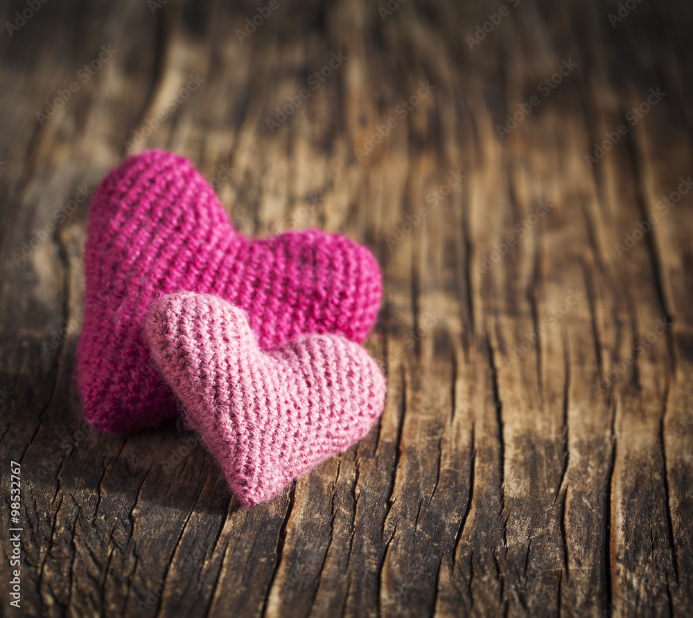 Fototapeta premium Two crochet pink hearts on wooden background