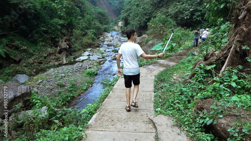 Young boy taking photo using selfie stick in jungle, super slow motion 120fps
