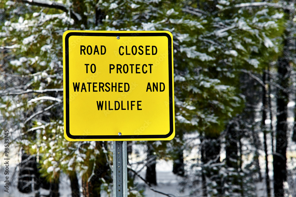 Road closed to protect watershed and wildlife sign in wilderness with snow