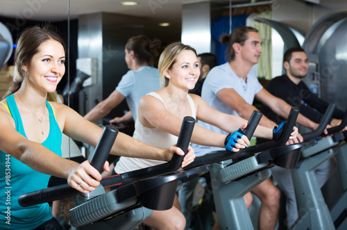 adults riding stationary bicycles in fitness club