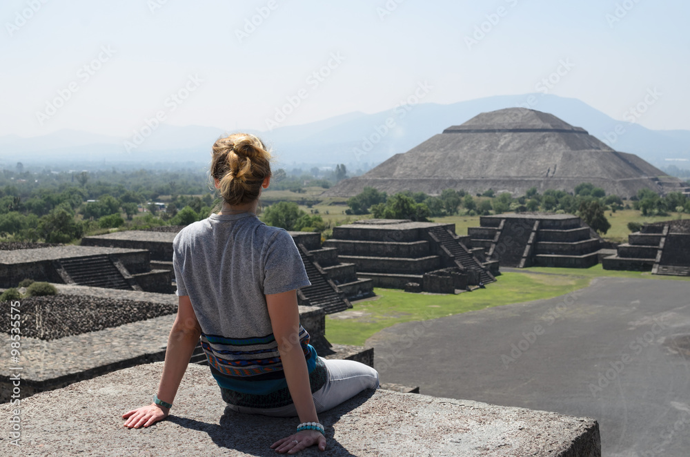 Young woman sitting on the top of pyramid overlooking Teotihuacan