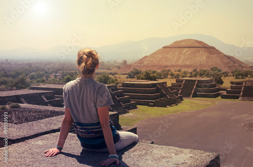 Young woman sitting on the top of pyramid overlooking Teotihuacan 