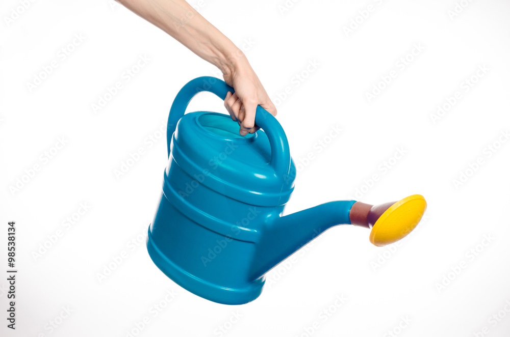 Obraz premium Caring for the plants and the garden theme: man's hand holding a large blue plastic watering can isolated on white background in studio