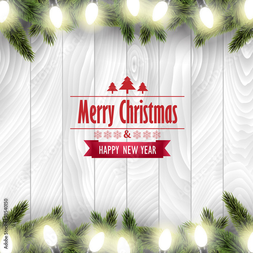 Christmas card with pine tree branches and Christmas lights on a white wooden board. 