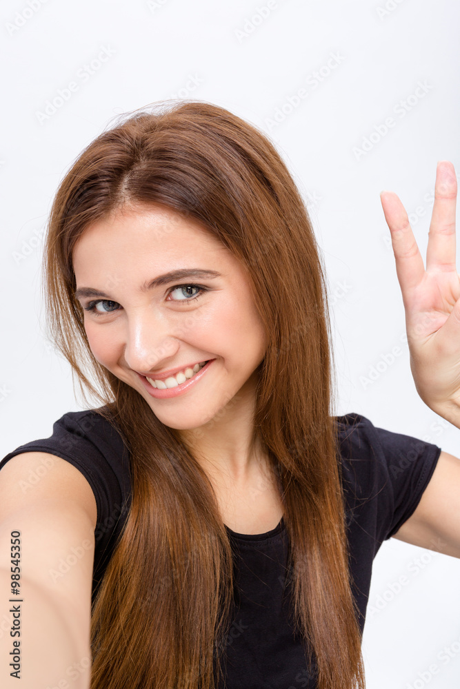 Positive smiling woman making selfie photo and showing peace sign Positive smiling woman making selfie photo and showing peace sign