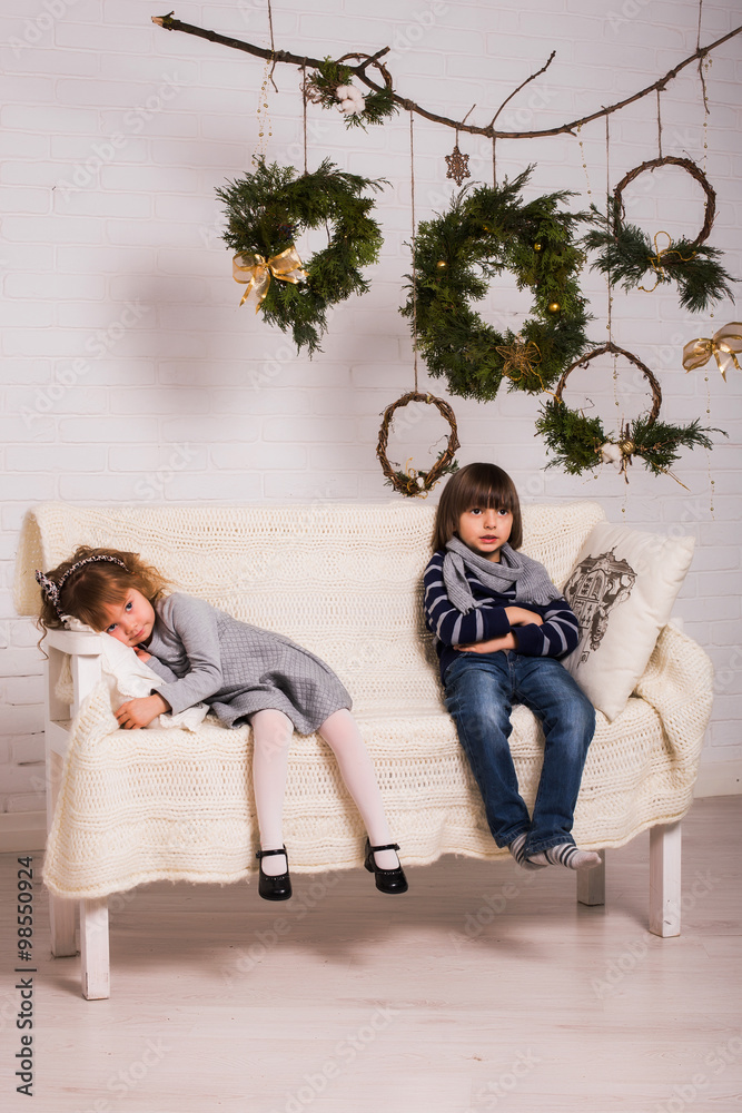 Naklejka premium Concept of christmas holiday / Handsome boy and cute small girl on Christmas background