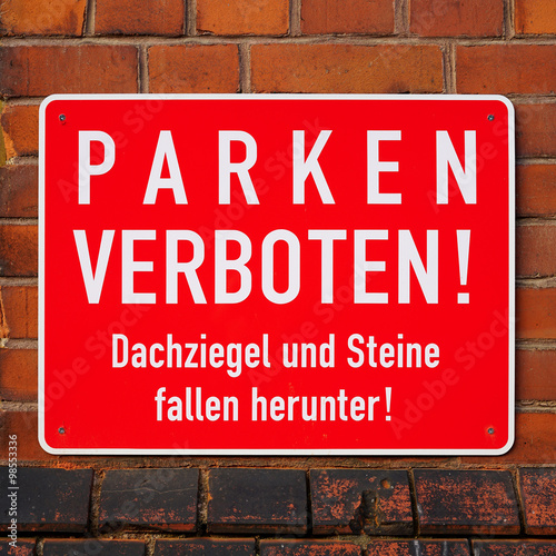 Schild mit der Aufschrift "Parken verboten, Dachziegel und Steine fallen herunter"