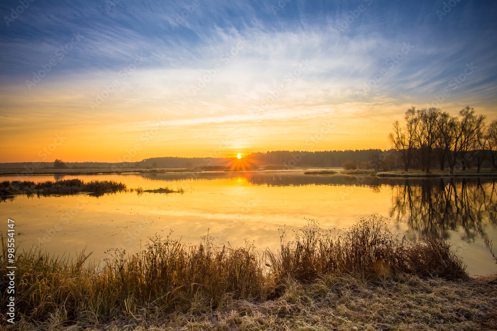 Bright beautiful Sunrise over Calm Lake, River and forest horizo