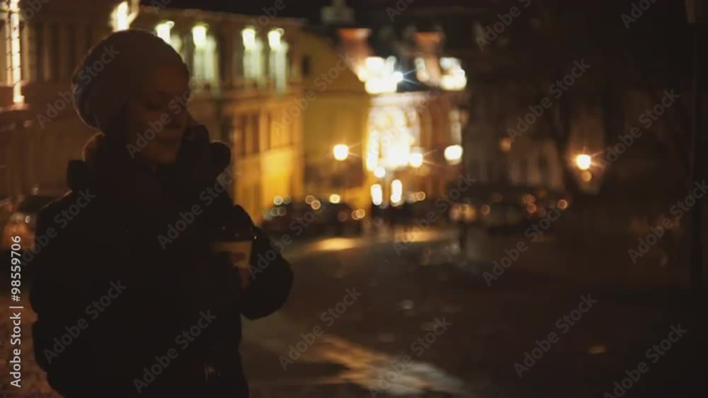 Woman on the street of the evening drinking coffee and talking on the phone Woman on the street of the evening drinking coffee and talking on the phone