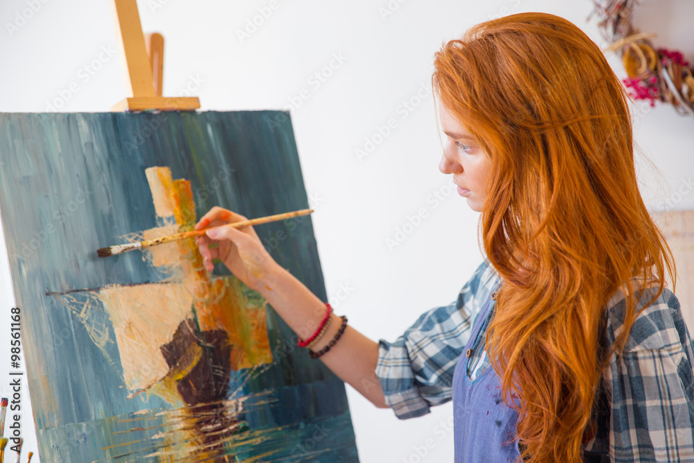 Obraz premium Beautiful serene young female painter painting picture in art workshop
