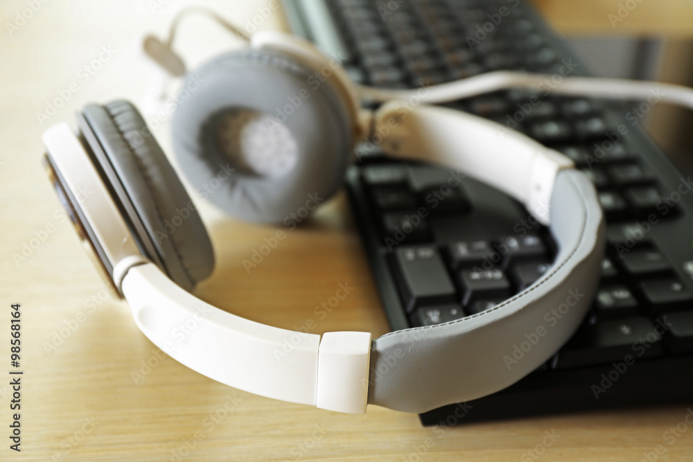 Headphones and keyboard on wooden table Headphones and keyboard on wooden table