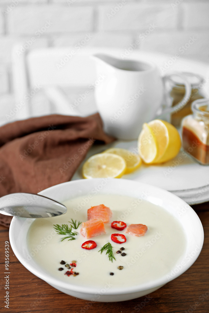 Delicious salmon cream soup with spoon on wooden table, close up Delicious salmon cream soup with spoon on wooden table, close up