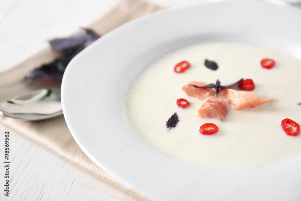 Delicious cream soup with fish and basil on white served table in the restaurant Delicious cream soup with fish and basil on white served table in the restaurant