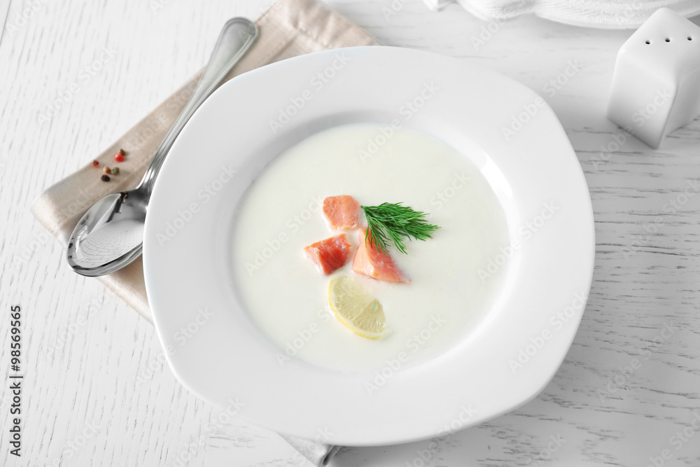 Delicious cream soup with fish and sliced lemon on white table in the restaurant Delicious cream soup with fish and sliced lemon on white table in the restaurant