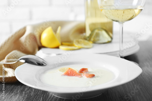 Served wooden table with tasty salmon cream soup  wine and lemon on it  close up
