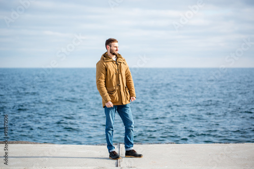 Thoughtful man standing on pier near the sea