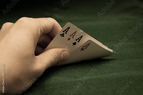 Hand with poker cards on green background