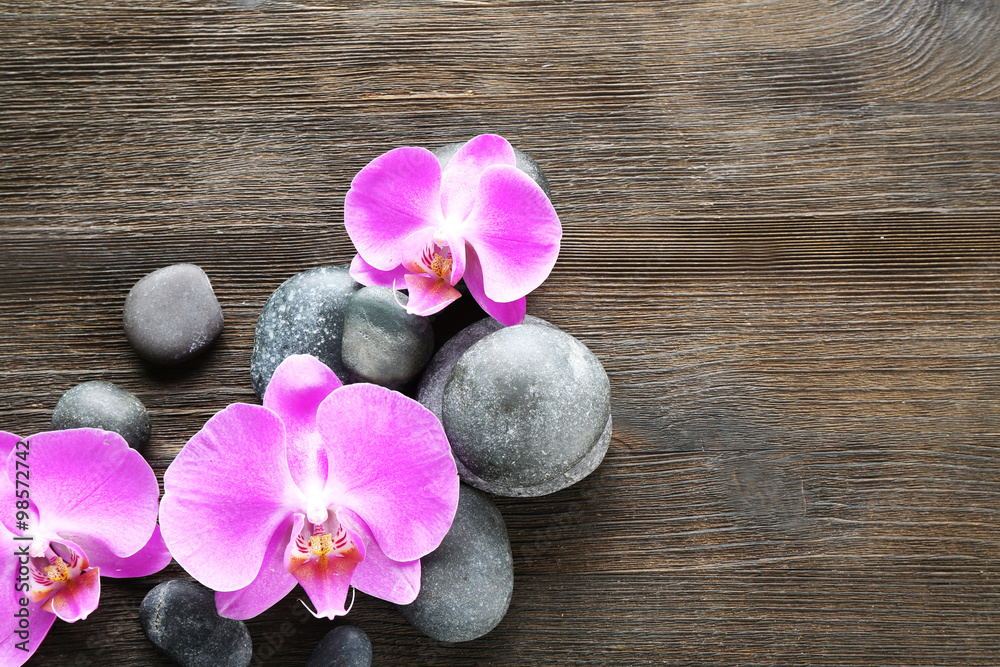 Fototapeta premium Spa stones and orchids on wooden background