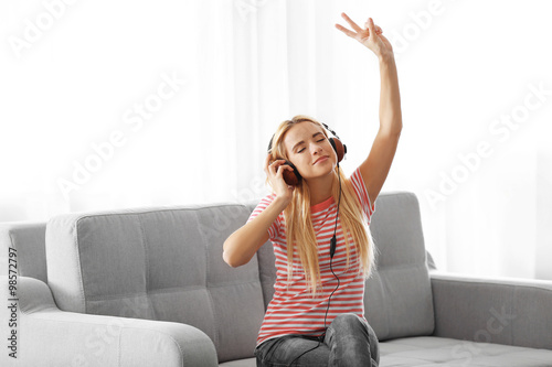 Young woman sitting and listening to music in a room