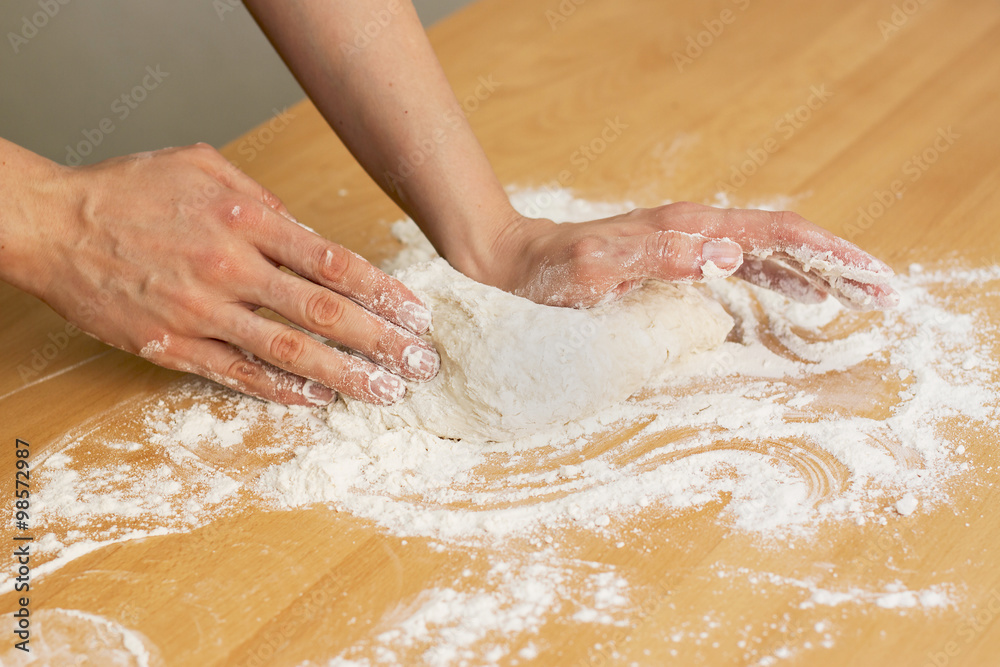 Hands knead the dough