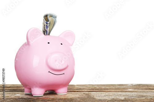 Piggy bank with banknote on wooden table, isolated on white