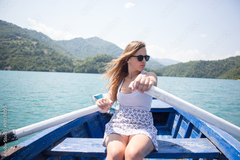 A young woman is rowing a boat on a summer day