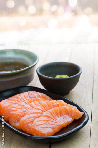 Sliced raw salmon on black plate with abstract background